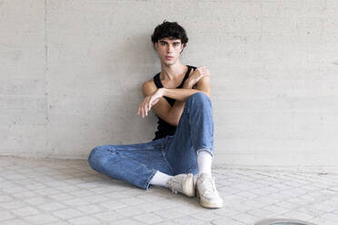 Young man sitting in front of wall - LMCF00540