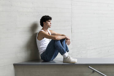 Thoughtful young man sitting on wall - LMCF00547