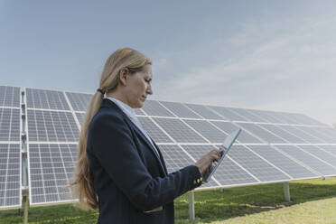 Engineer using tablet PC in front of solar panels - OSF02141