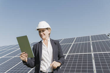 Lächelnder Ingenieur mit Tablet-PC vor einem Solarpanel - OSF02145