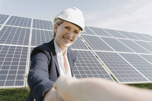 Happy engineer shaking hands in front of solar panels - OSF02148