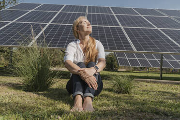 Älterer Ingenieur, der mit geschlossenen Augen vor einem Solarpanel sitzt - OSF02152