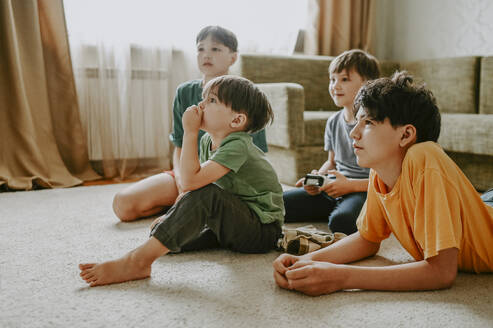 Brothers playing video game on carpet at home - ANAF02125