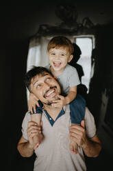 Lächelnder Vater trägt seinen Sohn nach Hause - ANAF02136