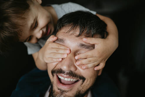 Smiling son covering father's eyes - ANAF02137