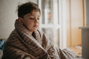 Kranker Junge, eingewickelt in eine Decke, zu Hause - ANAF02142