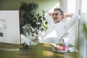 Entspannter Geschäftsmann bei einem Videogespräch über den Computer im Büro zu Hause - UUF30293