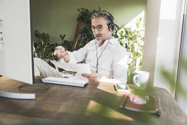 Freiberufler prüft Dokument und spricht über Headset im Home Office - UUF30307