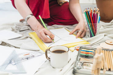 Künstlerin zeichnet auf Papier am Tisch - MGRF01048