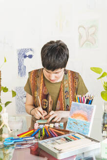 Künstlerin malt mit Pinsel am Tisch - MGRF01057