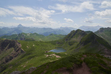 Picturesque view of mountain range with green grass and pond under cloudy blue sky in daylight at Aragon Pyrenees Aguas Tuertas Spain - ADSF47153