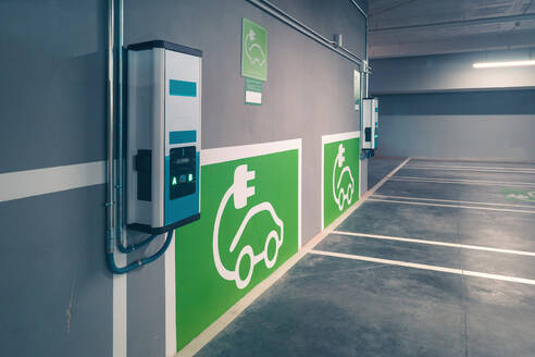Electric car charger signs and charging points for electric vehicles on gray wall at electric car charging station - ADSF47156