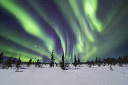 Picturesque view of starry sky with bright polar lights of aurora borealis with dynamic flickers covering blue sky over snowy mountain range in Lapland Norway - ADSF47178