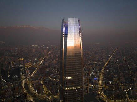 Aerial View Of Sunset Reflecting Off Tall Skyscraper With Cityscape And Andes Mountain Range In Distance, Santiago, Chile. - AAEF21906