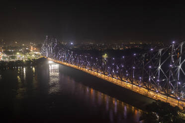 Aerial view of architectural landmark Howrah bridge or Rabindra Setu over the Hooghly River at night in Kolkata, West Bengal, India. - AAEF21970