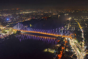 Luftaufnahme des architektonischen Wahrzeichens Howrah-Brücke oder Rabindra Setu über den Hooghly-Fluss bei Nacht in Kolkata, Westbengalen, Indien. - AAEF21974