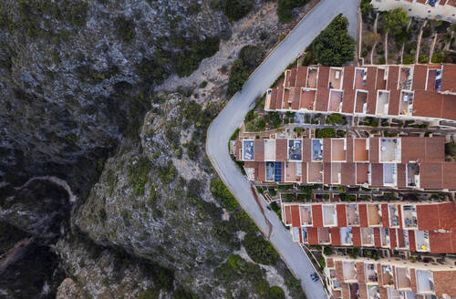 Luftaufnahme eines lebendigen Stadtbilds mit geordneter Architektur, das durch eine Asphaltstraße von einer Klippe getrennt ist, Zona Encinas, Cumbre del Sol, Alicante, Spanien. - AAEF22092