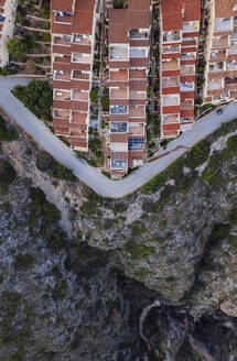 Luftaufnahme eines lebendigen Stadtbilds mit geordneter Architektur, das durch eine Asphaltstraße von einer Klippe getrennt ist, Zona Encinas, Cumbre del Sol, Alicante, Spanien. - AAEF22093