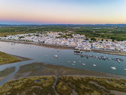 Aerial view of boats moored along the pier at sunset in Santa Luzia, Faro, Algarve, Portugal. - AAEF22116