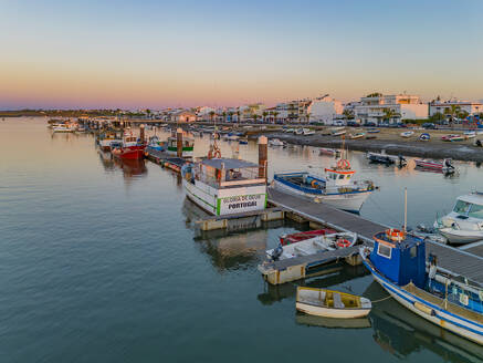 Faro, Portugal - 27 July 2023: Aerial view of boats moored along the pier at sunset in Santa Luzia, Faro, Algarve, Portugal. - AAEF22117