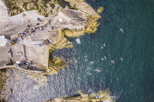 Luftaufnahme von oben nach unten von Menschen im Wasser im Meer von Sandycove Beach, Dalkey, Irland. - AAEF22129