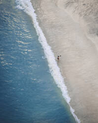 Aerial view of a person with a surfboard along the shoreline at Lantau island, Cheung sha Beach, Hong Kong. - AAEF22180
