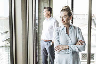 Smiling blond businesswoman with businessman standing in background - UUF30379