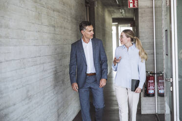 Businessman and businesswoman having discussion together in office - UUF30440