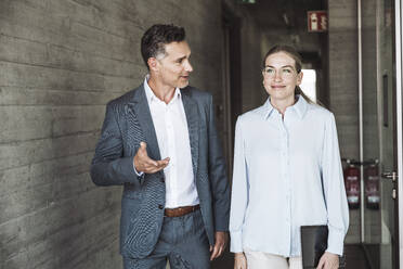 Smiling businessman and businesswoman having discussion together in office - UUF30441