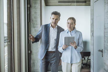 Businessman discussing with colleague using tablet PC - UUF30444