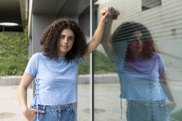 Junge Frau steht an einer Glaswand - LMCF00559