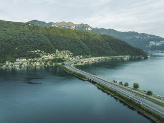 Luftaufnahme einer Straße über den Luganersee bei Sonnenuntergang, Melide, Tessin, Schweiz. - AAEF22550