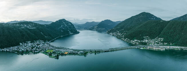 Panoramic aerial view of Melide, a small town along the Lugano Lake with a road bridge crossing the lake at sunset in Ticino, Switzerland. - AAEF22558