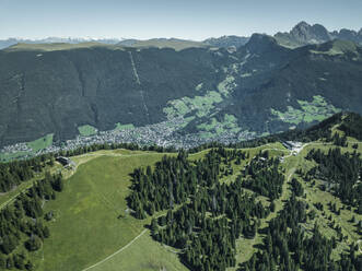 Aerial view of the mountain ridge at the top of Alpe di Siusi (Seiser Alm) on the Dolomites mountains with Ortisei town in background, Trentino, South Tyrol in Northern Italy. - AAEF22626