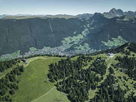 Luftaufnahme des Bergrückens auf der Seiser Alm in den Dolomiten mit der Stadt St. Ulrich im Hintergrund, Trentino, Südtirol in Norditalien. - AAEF22626