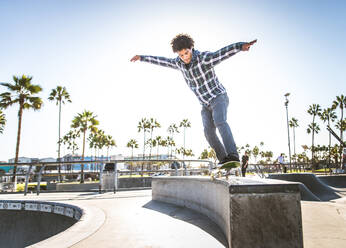 Cool skateboarder outdoors - Afroamerican guy jumping with his skate and performing a trick - DMDF04998