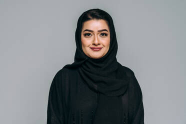 Schöne arabische Frau aus dem Mittleren Osten mit traditionellem Abaya-Kleid im Atelier - Arabisches muslimisches erwachsenes Frauenporträt in Dubai, Vereinigte Arabische Emirate - DMDF05018