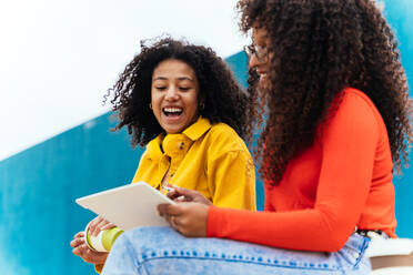 Junge glückliche Frauen, die an einem Tablet lernen. Jugendliche, die nach der Schule Zeit miteinander verbringen - DMDF05155