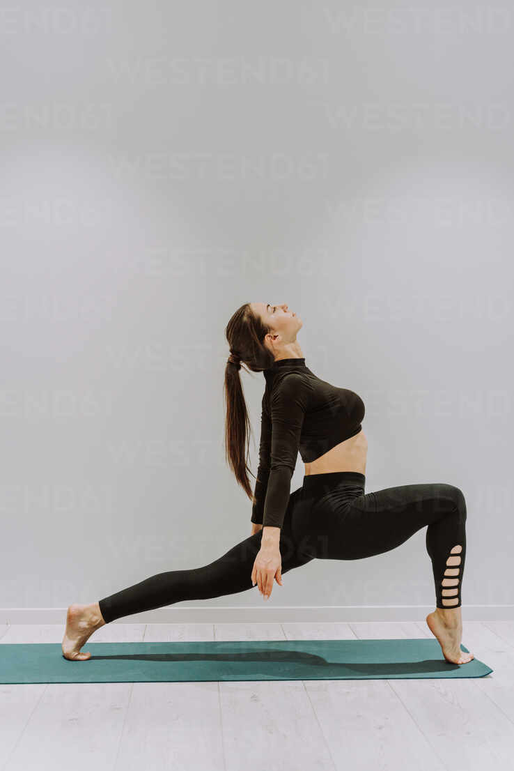 Beautiful athletic woman training in a gym, doing stretching exercises  before the workout - Pretty young girl training alone stock photo