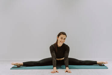 Beautiful athletic woman training in a gym, doing stretching exercises before the workout - Pretty young girl training alone - DMDF05364