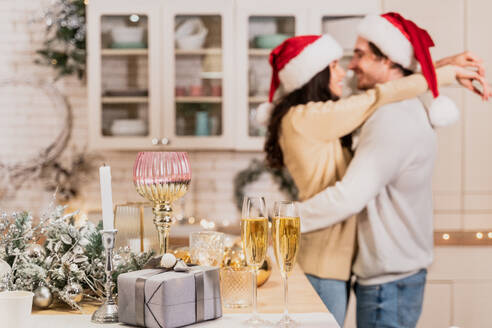 Happy beautiful couple of lovers celebrating Christmas at home - Winter holiday season, celebration of xmas eve in a decorated apartment - DMDF05368