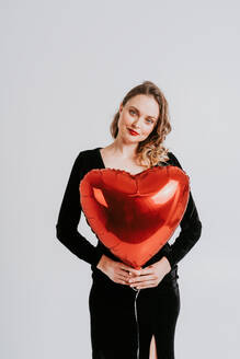 Beautiful woman celebrating valentine's day and holding heart shaped air ballon - DMDF05395