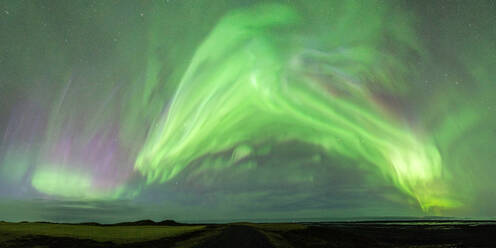 Spectacular scenery of green Northern lights illuminating dark sky over green meadow and mountain - ADSF47200