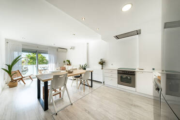 Interior of contemporary kitchen and dining room with white furniture designed in minimal style in apartment - ADSF47316