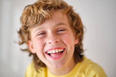 Smiling kid in yellow outfit with brown wavy hair looking at camera in daylight - ADSF47320