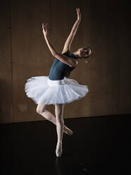 Full body of slim female ballerina in tutu and pointe shoes dancing ballet role during rehearsal in studio - ADSF47408