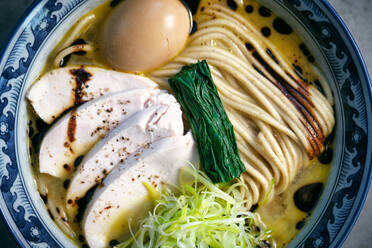 Top view of tasty Japanese noodle soup with boiled egg and fresh vegetables in broth with soy sauce in bowl - ADSF47414