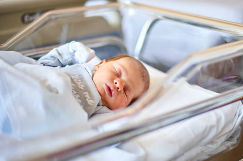 Newborn baby sleeping in its hospital crib - ADSF47435