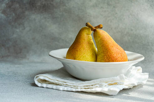 White marble plate with fresh juicy pears placed on a concrete table - ADSF47485