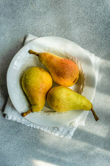 Top view of white marble plate with fresh juicy pears placed on a concrete table - ADSF47486